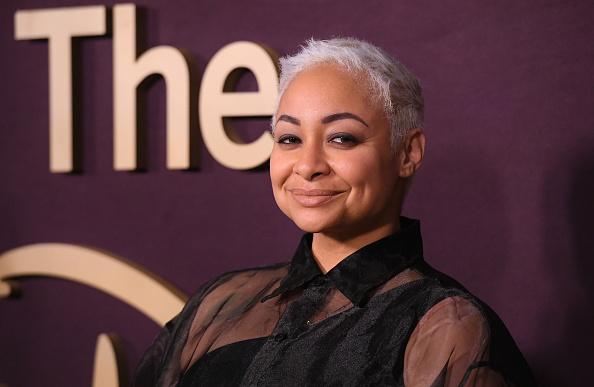 Raven-Symoné at a red carpet event, wearing a sheer black top over a black inner shirt