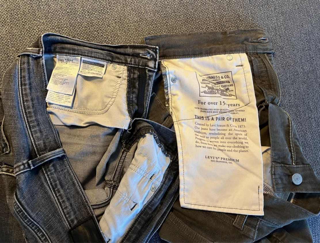 Two pairs of jeans lying on a flat surface, showing the labels and inner tags detailing Levi's Premium and sustainability information