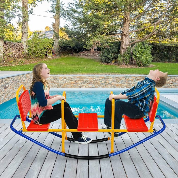 Two children on a rocking seesaw on a deck