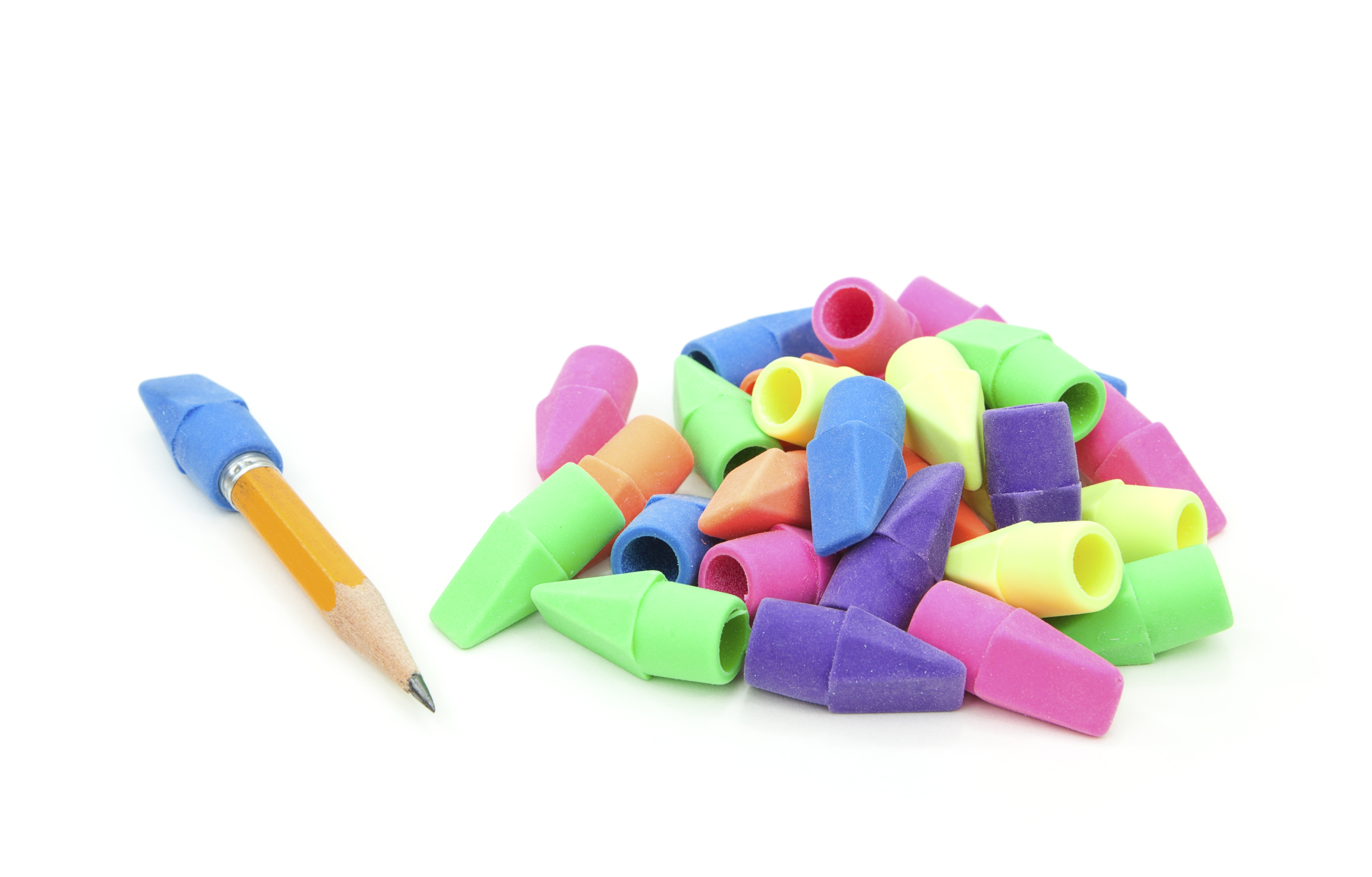 A sharpened pencil lies next to a pile of multicolored pencil erasers