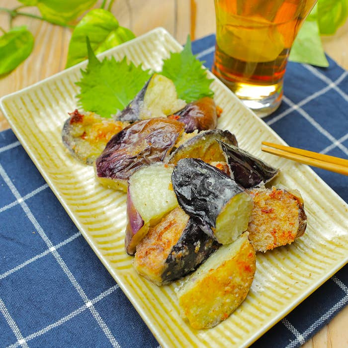 皿に盛られたなすがテーブルに置かれている。隣に飲み物と箸も見える。