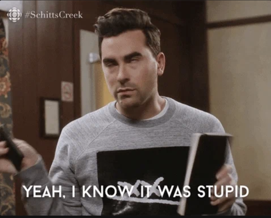Dan Levy from Schitt's Creek, holding a book and shaking his head, with the caption, &quot;YEAH, I KNOW IT WAS STUPID.&quot;