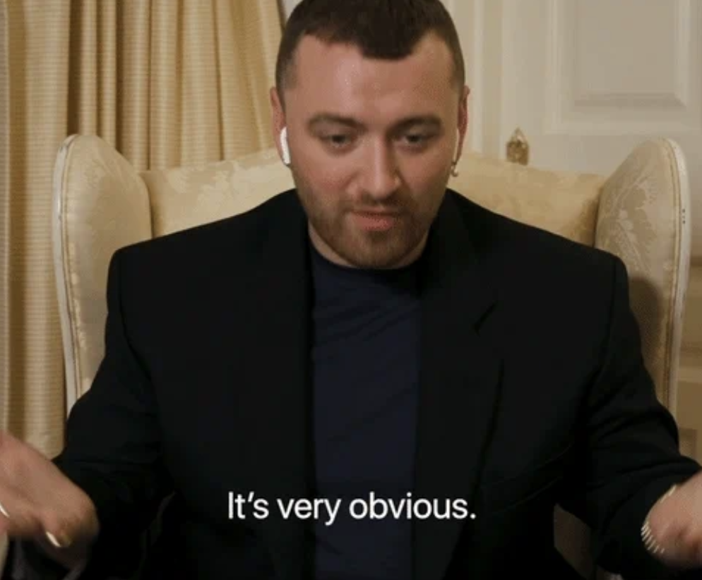 Sam Smith sitting in a chair, wearing a dark blazer and wireless earbuds, with the subtitle &quot;It's very obvious.&quot;