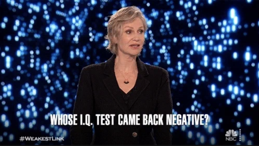 Jane Lynch in a black suit on 'Weakest Link' game show with text overlay: &quot;Whose I.Q. test came back negative?&quot; and hashtags #WEAKESTLINK, #NBC