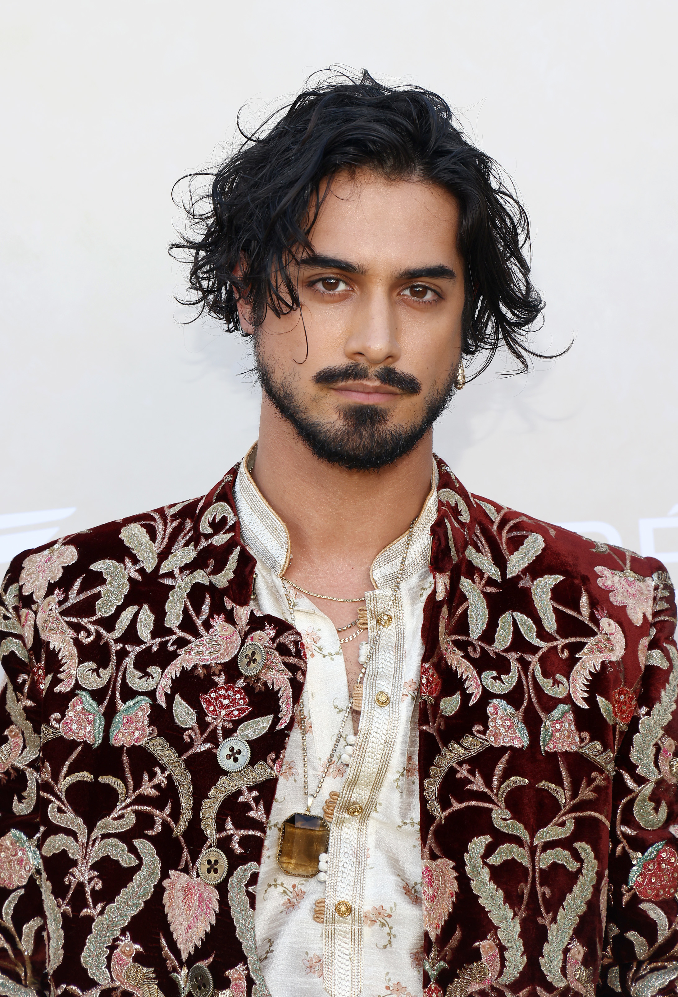 Avan Jogia in a velvet, ornately embroidered jacket over a light floral-patterned shirt