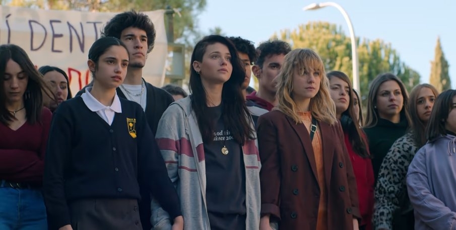 Grupo de jóvenes con expresión seria sosteniendo pancartas en una protesta. Todos miran hacia adelante con determinación