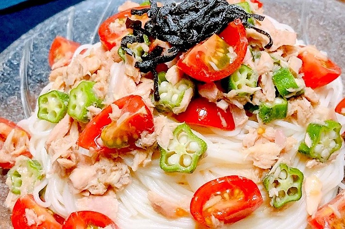 透明な皿に盛られた冷やしそうめん、トマト、オクラ、ツナ、海苔がトッピングされています。