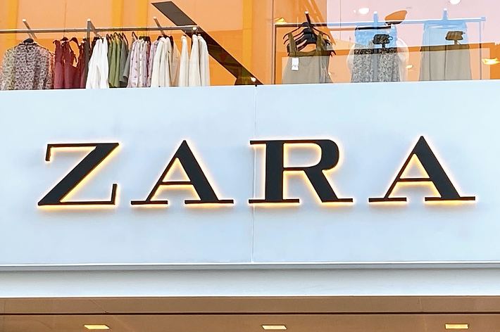Storefront of a Zara clothing store with a display of hanging clothes in the window