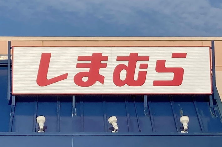 Retail store with sign in Japanese kanji characters. The store&rsquo;s exterior features blue accents and a handicap parking symbol is visible