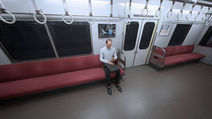 男性が地下鉄車両の座席に座っており、膝の上にバッグを置いています。車内は他に乗客はいません。