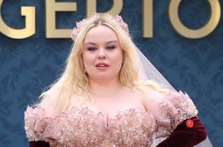 Nicola Coughlan at a red carpet event in an elaborate gown with floral embellishments and a flowered headpiece