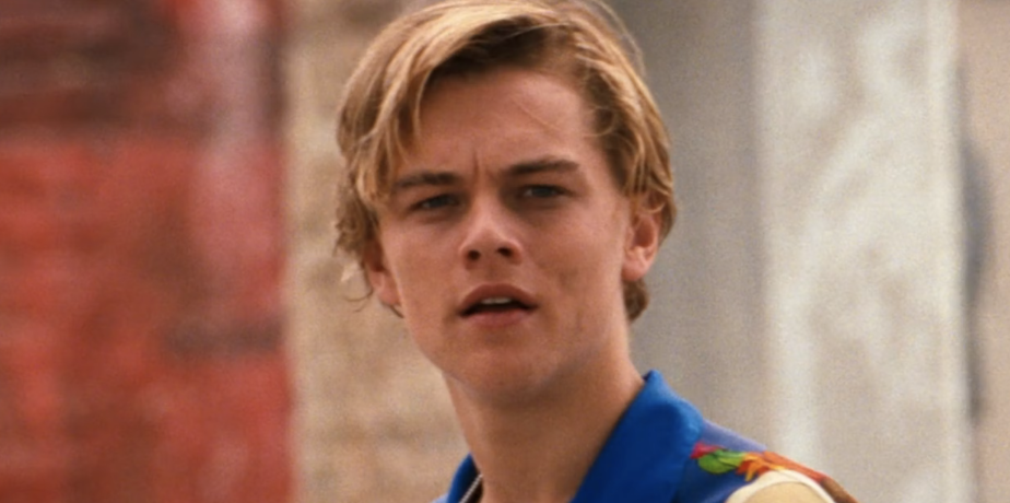 Leonardo DiCaprio in a casual scene, wearing a blue jacket with embroidery, looking off to the side