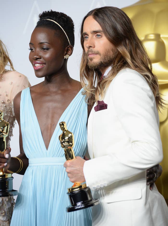 Lupita Nyong&#x27;o in a v-neck gown and Jared Leto in a light suit holding Oscar trophies after their wins