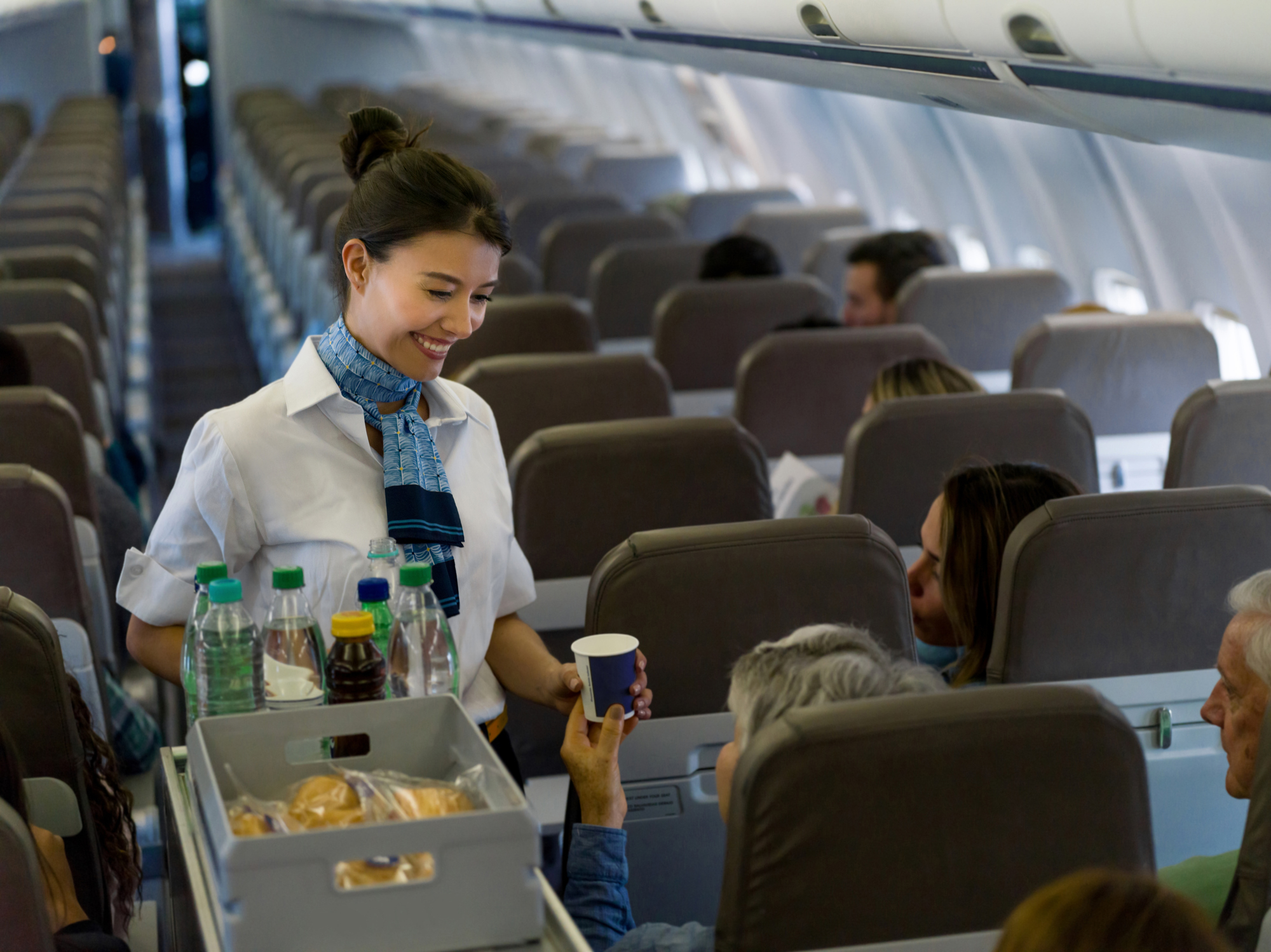 Flight attendant serves drinks and snacks to passengers on an airplane
