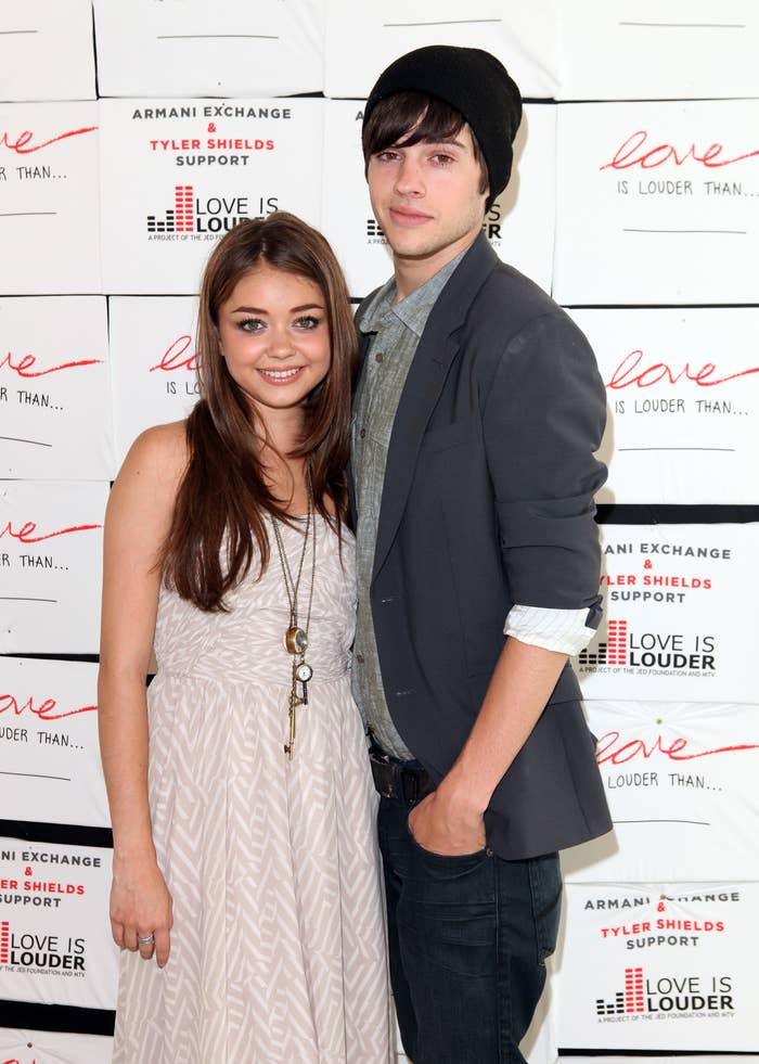 Sarah Hyland wearing a patterned dress and Matt Prokop in a casual outfit and beanie at an Armani Exchange event for Love is Louder campaign