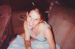 Young woman, unknown, wearing a tank top and sitting in the backseat of a car, playfully sticking her tongue out with chopsticks in her hair