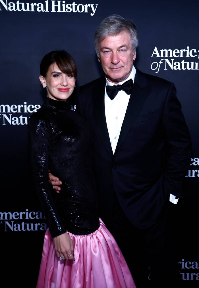 Hilaria Baldwin in a long-sleeve top and pink skirt, and Alec Baldwin in a tuxedo, posing together at the American Museum of Natural History event