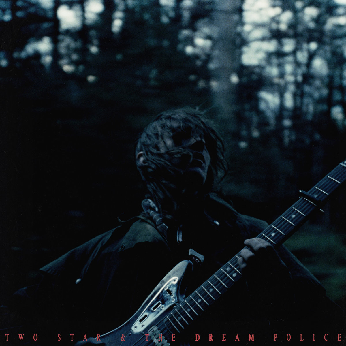 Cover art for &quot;Two Star &amp; The Dream Police&quot; featuring a musician in a forest, holding an electric guitar, with dark, moody lighting