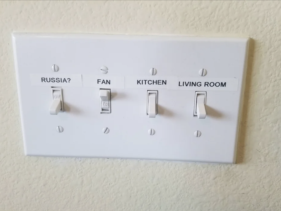 Light switch panel with switches labeled "Russia?" "Fan" "Kitchen" and "Living Room."