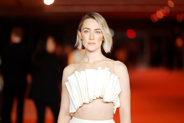 Saoirse Ronan poses on the red carpet, wearing an elegant strapless top with a ruffled design