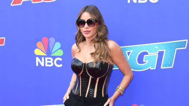 Sofía Vergara on the red carpet, wearing a strapless black corset top with gold details and black pants. She's also wearing sunglasses and gold bracelets