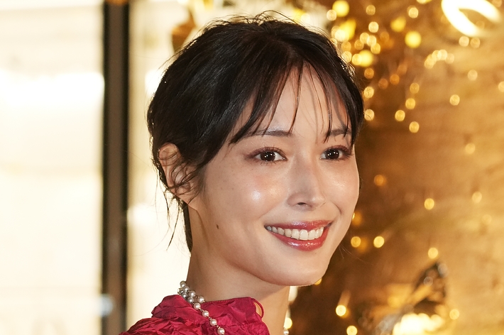 この画像には、鮮やかな服を着ている女性の肖像が含まれています。名前はわかりません。