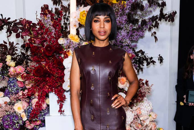 Kerry Washington wears a floor-length leather dress with floral detailing as she poses in front of a colorful floral backdrop at an event