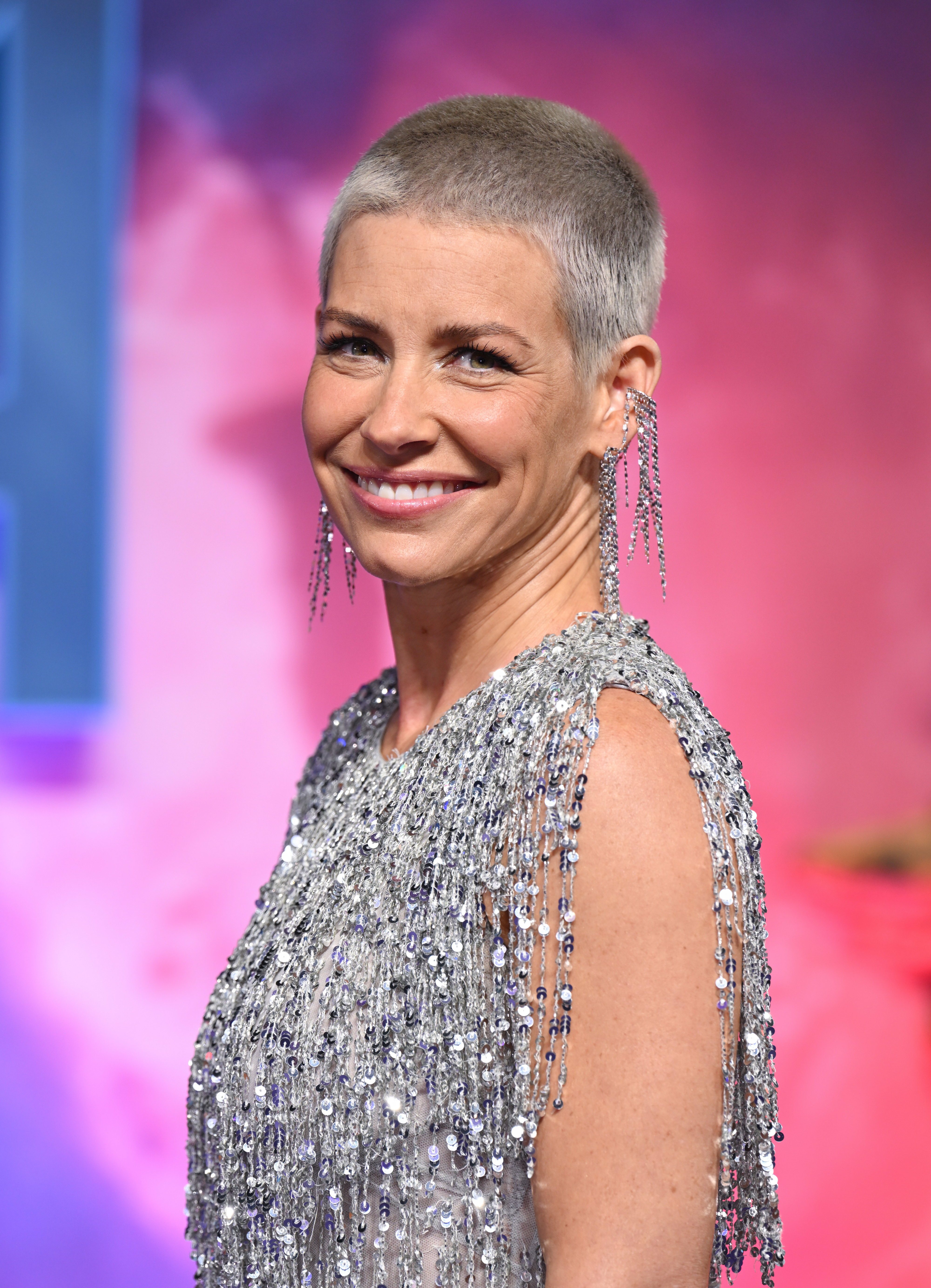Evangeline Lilly smiles on the red carpet, dressed in a shimmering, beaded dress with chandelier earrings