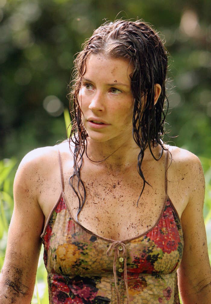Evangeline Lilly stands outdoors with wet hair and muddy skin, wearing a floral-patterned tank top