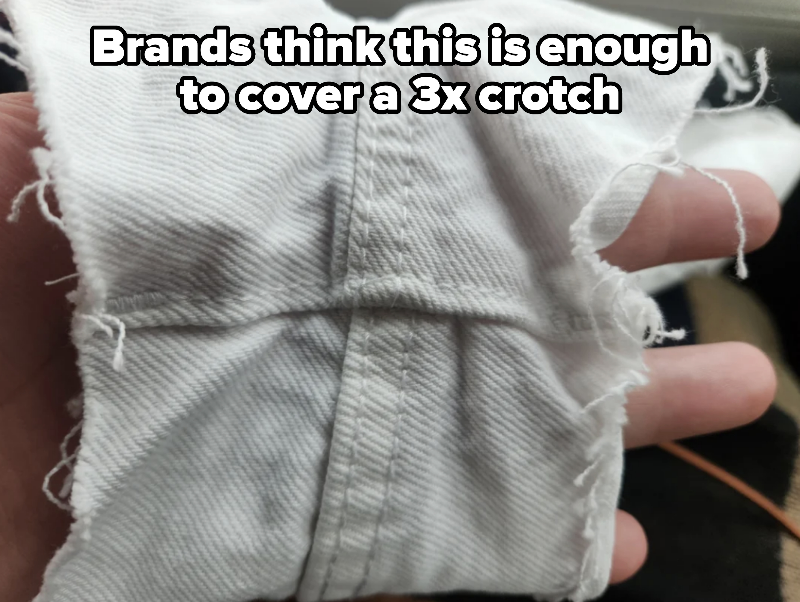 A hand holds a piece of ripped white fabric with visible seams and frayed edges