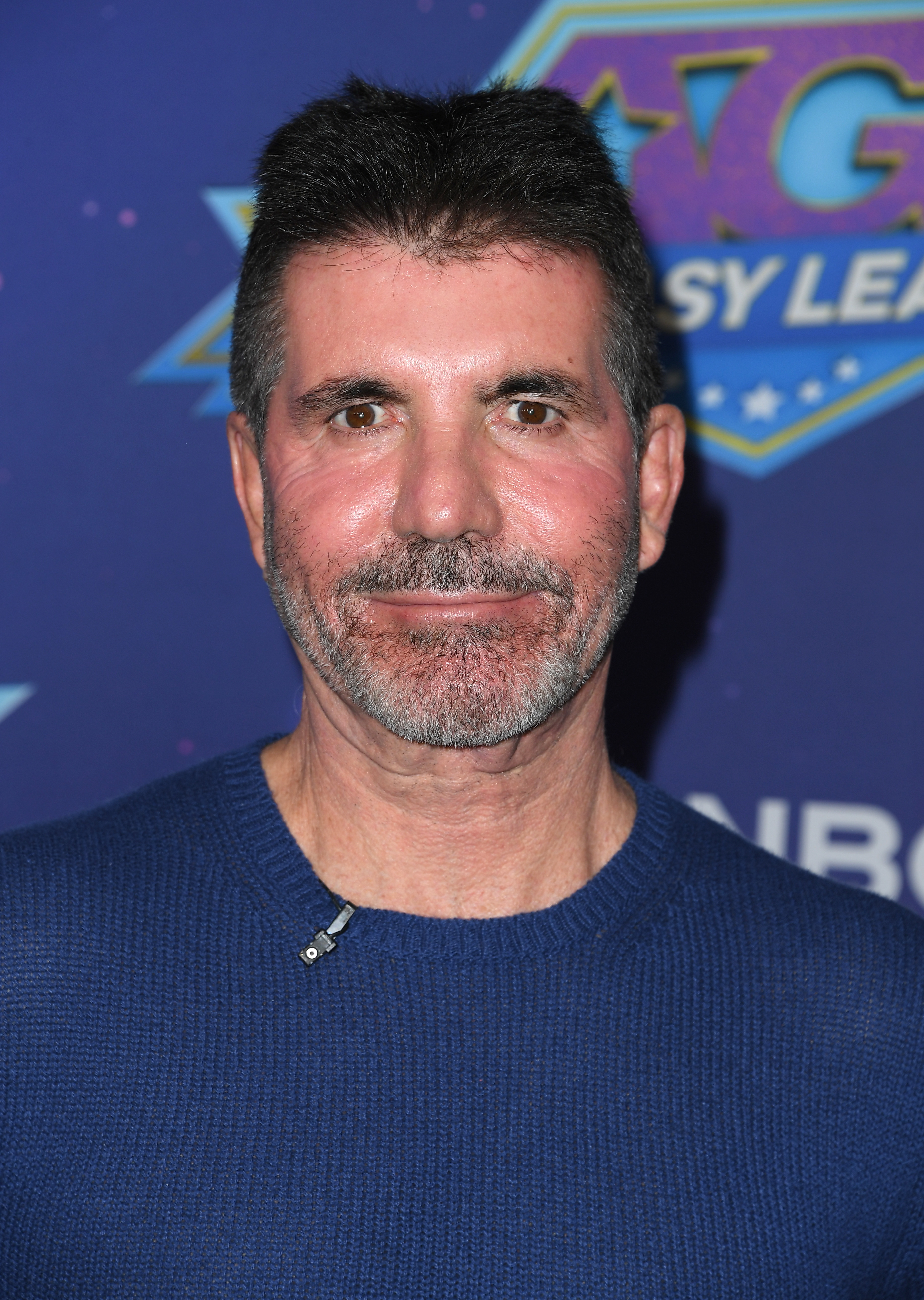Simon Cowell poses in a dark knit sweater at an event