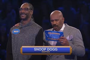 Snoop Dogg and Steve Harvey on a game show stage. Snoop Dogg is smiling, and Steve Harvey is reading a card