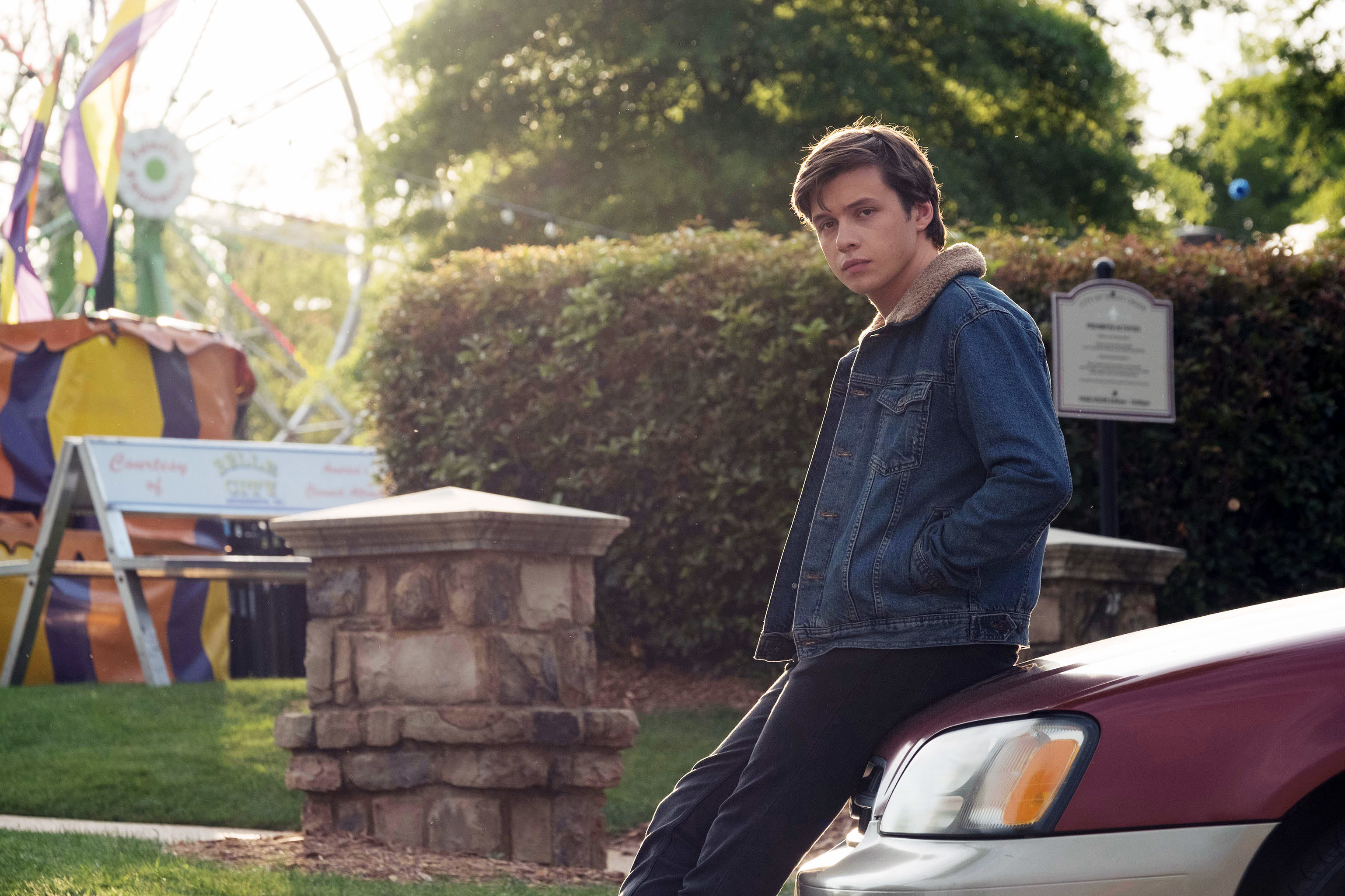 Nick Robinson leans against a car at a carnival in a scene from the movie &quot;Love, Simon.&quot;