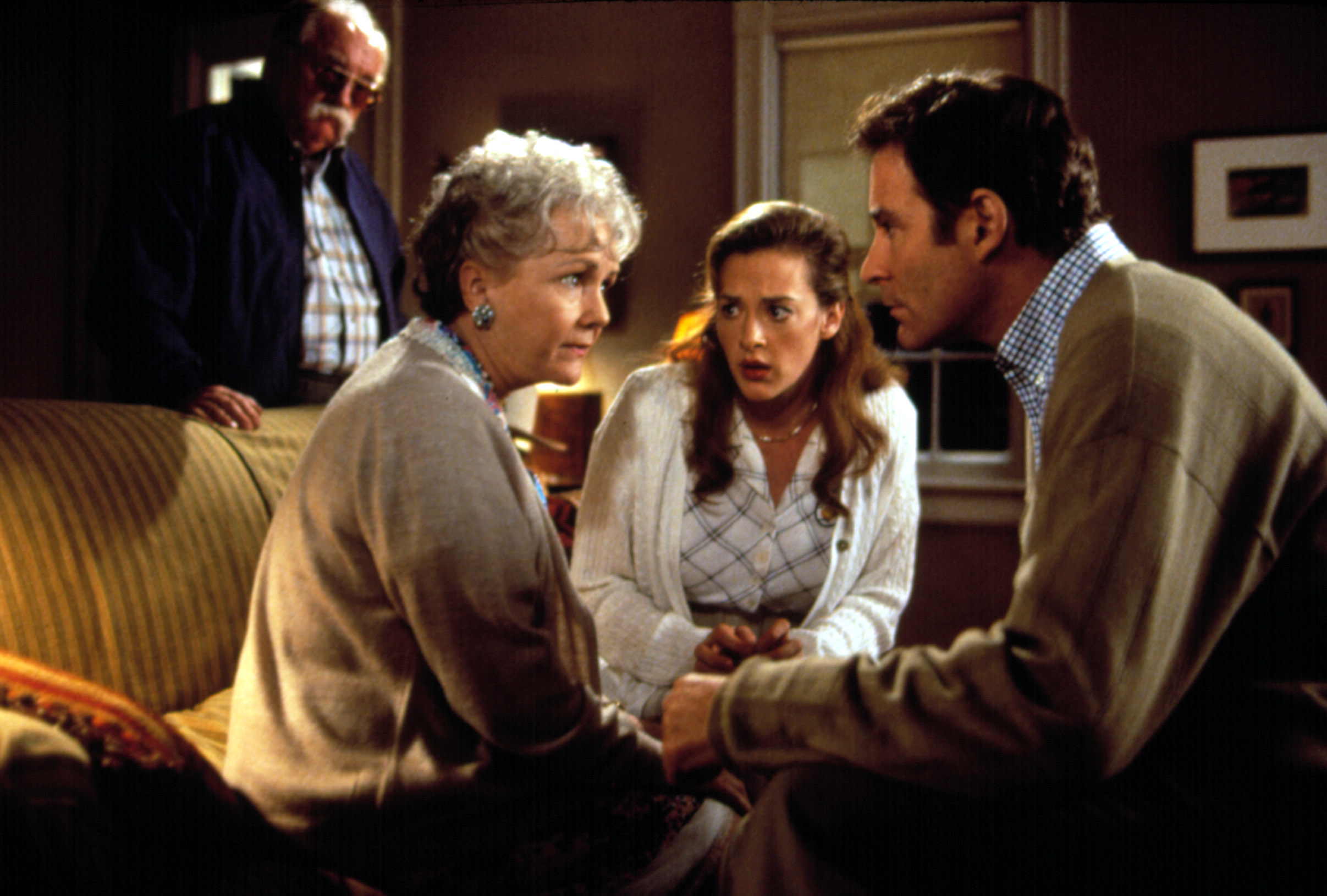 Scene from &quot;The Dead&quot;: two older adults, Anjelica Huston and another female, sit on a couch with a young woman, and Donal McCann leans in; an older man in the background