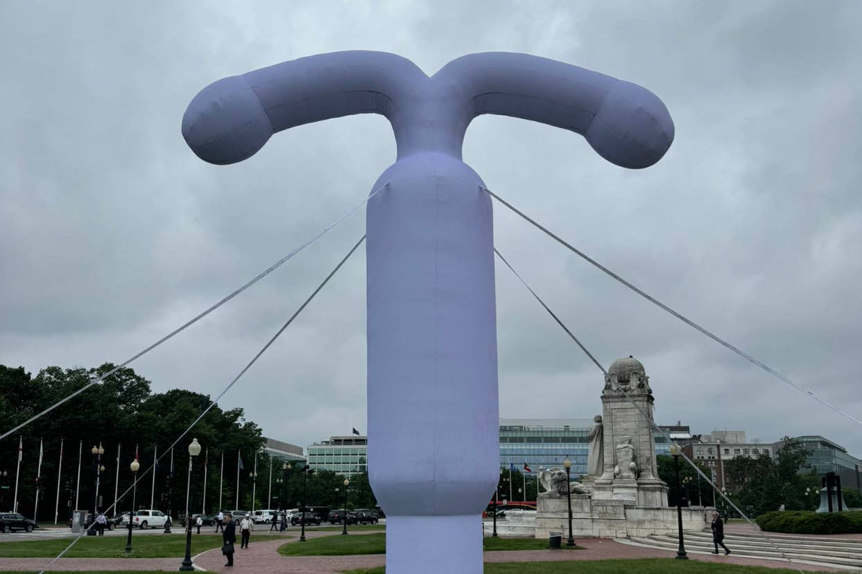 A large inflatable IUD installation is displayed outdoors near a historic monument and a modern building