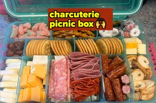 Charcuterie picnic box with crackers, cheeses, salami, pepperoni, pretzels, nuts, gummy candies, and cookies