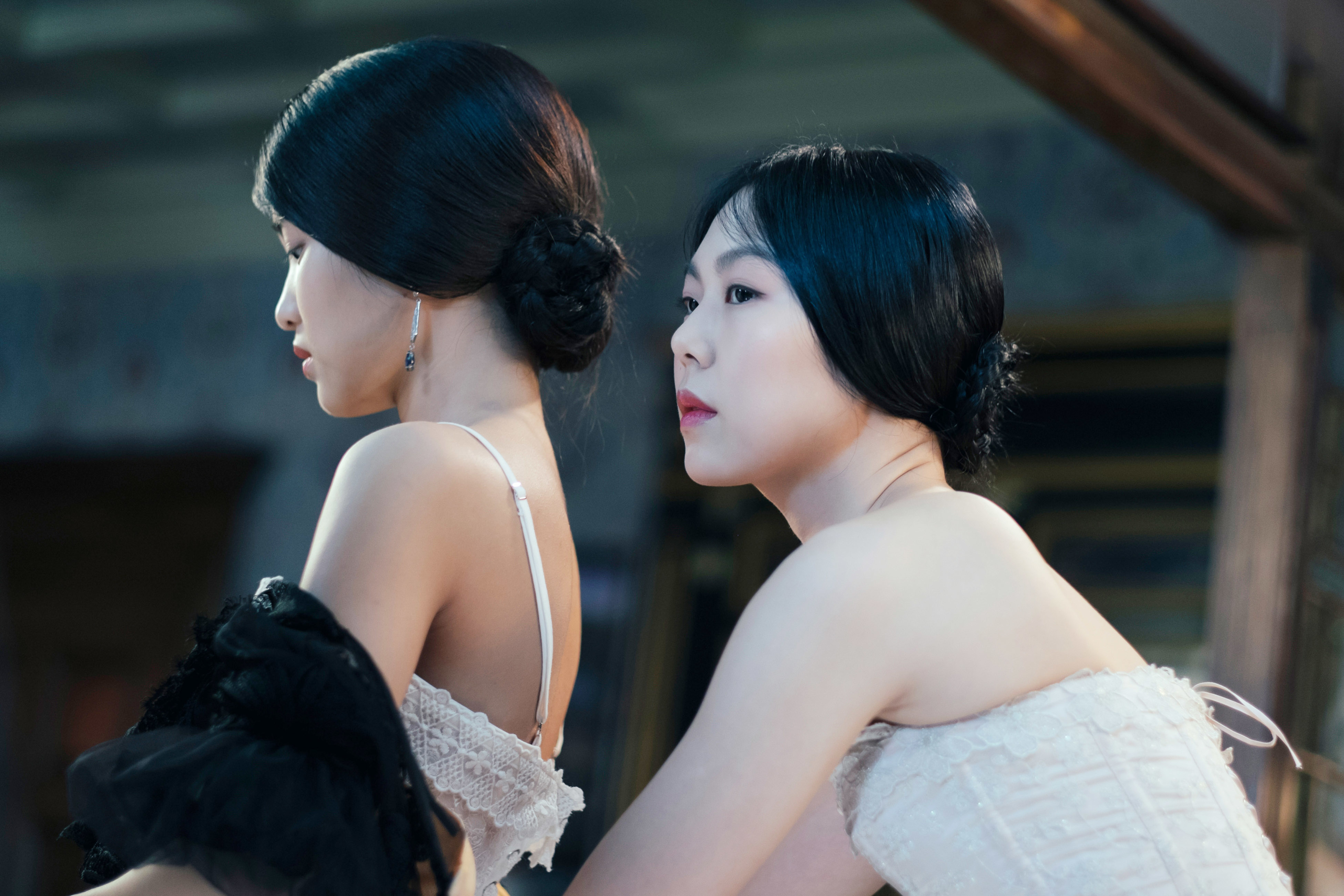 Kim Tae-ri and Kim Min-hee, in period costumes, appear in a scene from &quot;The Handmaiden,&quot; showcasing elegant updos and vintage lace attire