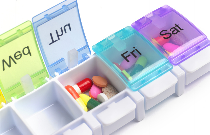 A weekly pill organizer with sections labeled &quot;Sun,&quot; &quot;Mon,&quot; &quot;Fri,&quot; and &quot;Sat,&quot; each containing various pills and tablets