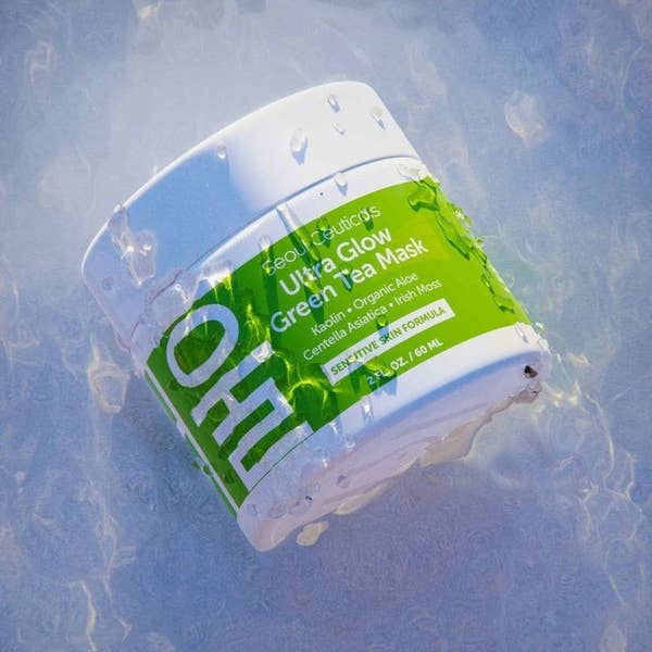 A jar of SeoulCeuticals Ultra Glow Green Tea Mask on a reflective surface. The mask features a green label highlighting key ingredients like kaolin, organic aloe, and matcha
