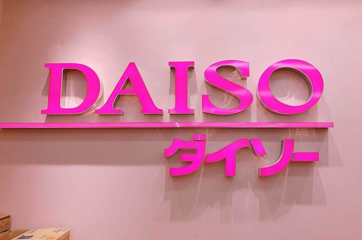 DAISOストアのロゴが壁に表示されています。ロゴは「DAISO」と「ダイソー」のテキストを含んでいます。
