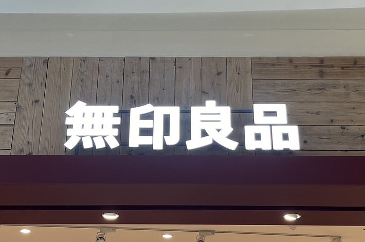 店舗の入口に掲げられた「無印良品」と書かれた看板。店内は衣料品が並べられている。