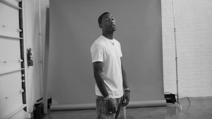 A person in a casual outfit of a plain white t-shirt and jeans stands in front of a photography backdrop in a studio setting