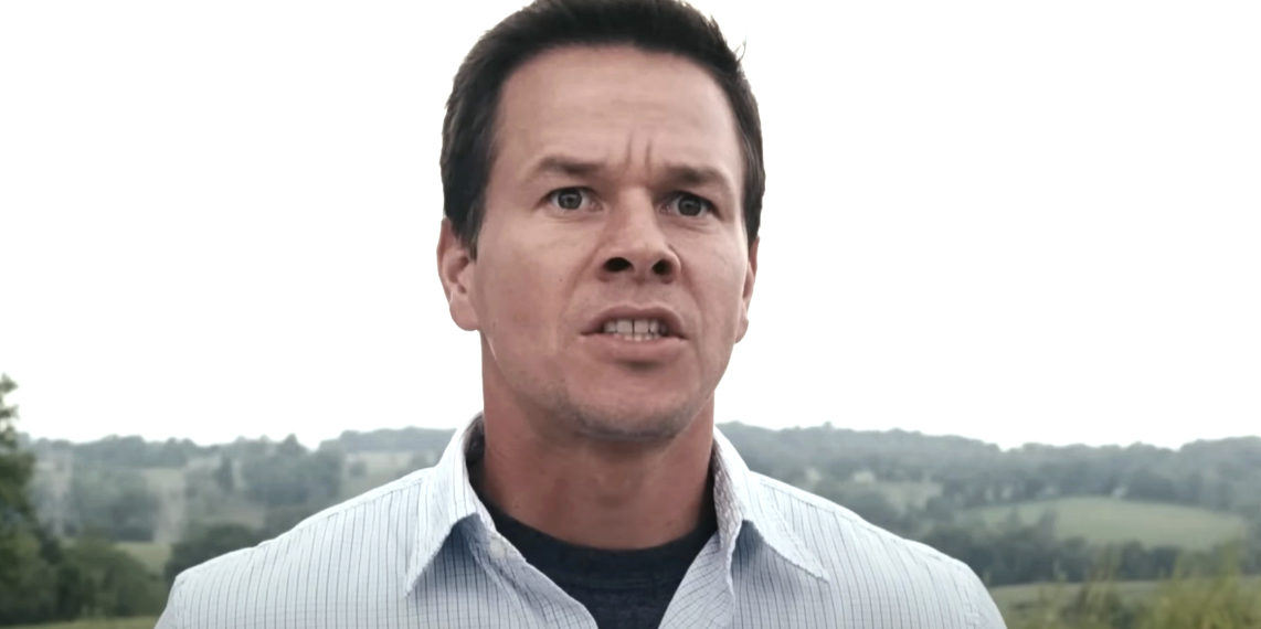 Mark Wahlberg in an intense scene from a movie, looking concerned with a scenic outdoor background