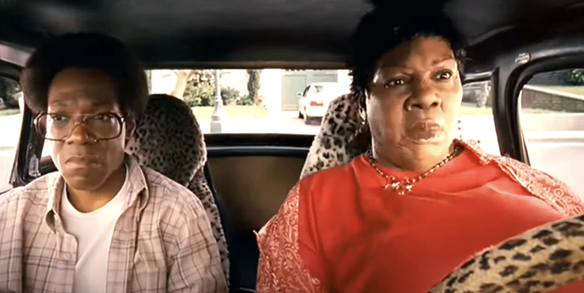 Loretta Devine and David Alan Grier are sitting in a car with leopard-print seat covers, appearing worried or startled