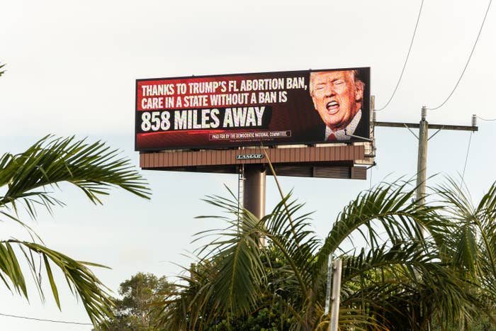 Billboard showing Donald Trump's face, criticizing the Florida abortion ban and stating that care in a state without a ban is 858 miles away