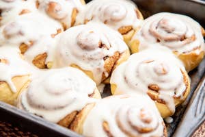 Close-up of a tray filled with freshly baked cinnamon rolls, topped with a generous amount of white icing
