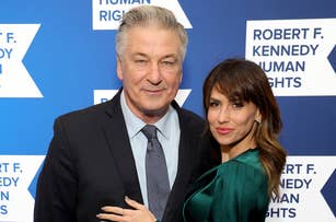 Alec Baldwin in a navy suit and Hilaria Baldwin in a green satin top and black pants pose together at the Robert F. Kennedy Human Rights event
