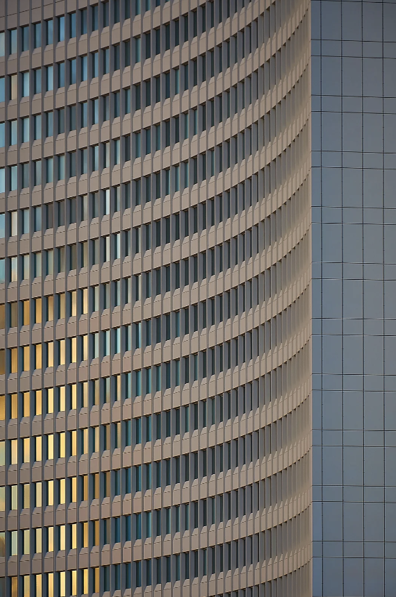 Curved facade of a modern high-rise building, showcasing repeating patterns of windows and architectural elements
