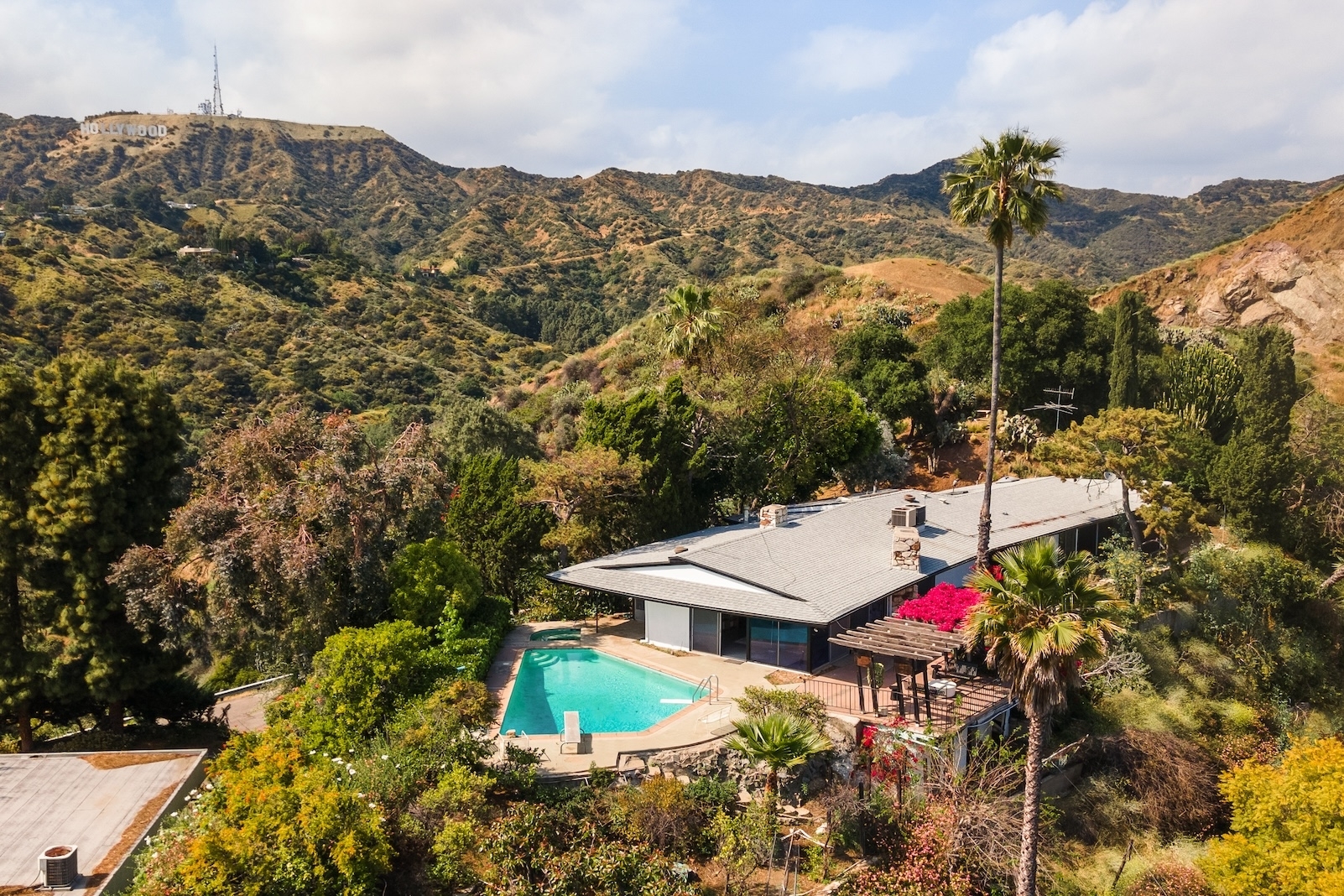 Aerial view of a luxurious house with a pool nestled in a lush, mountainous area near the Hollywood Sign in Los Angeles
