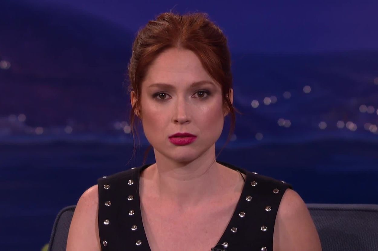 Ellie Kemper on a talk show set, wearing a sleeveless dress with studded embellishments